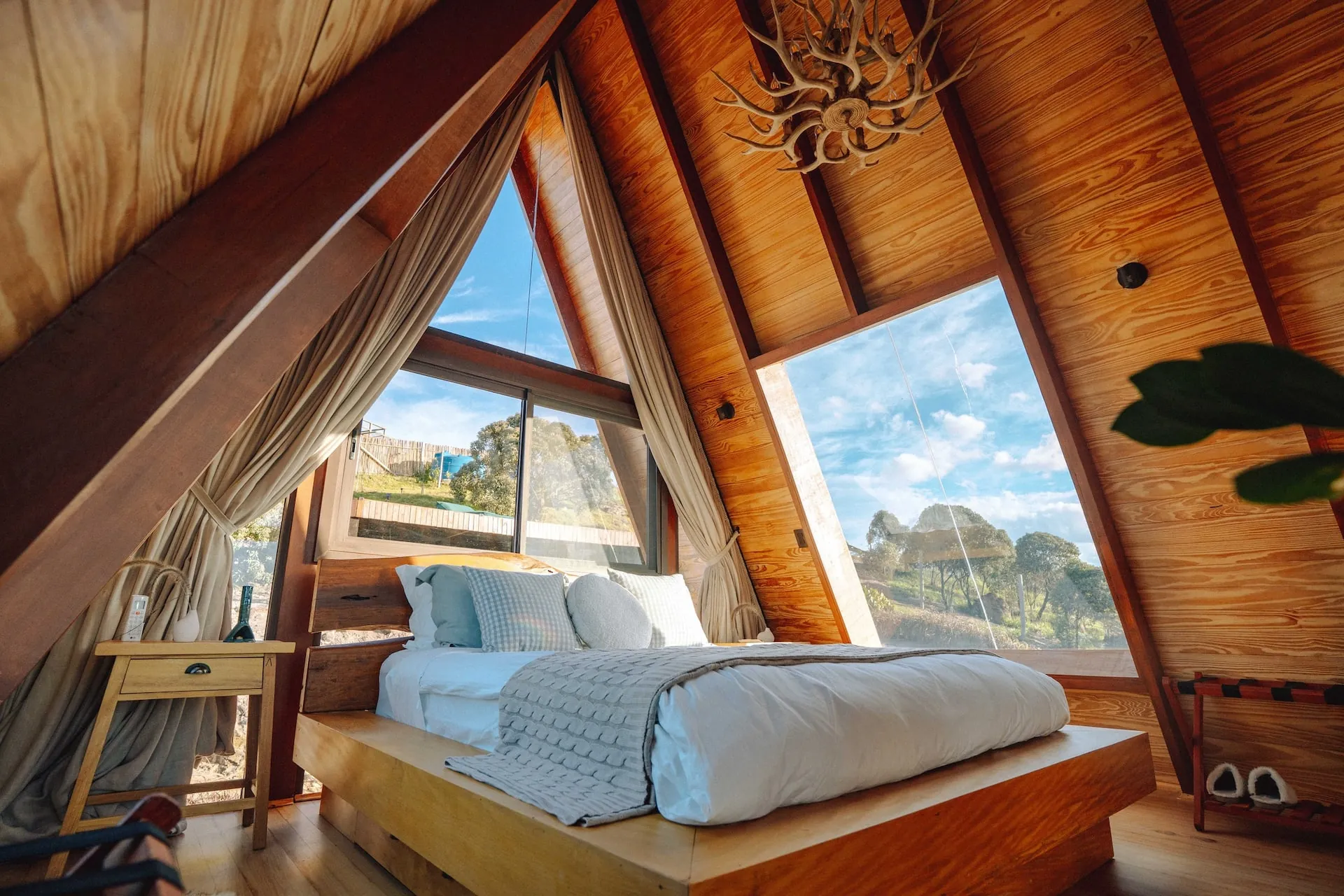 Cama queen no mezanino com as janelas triangulares para as montanhas